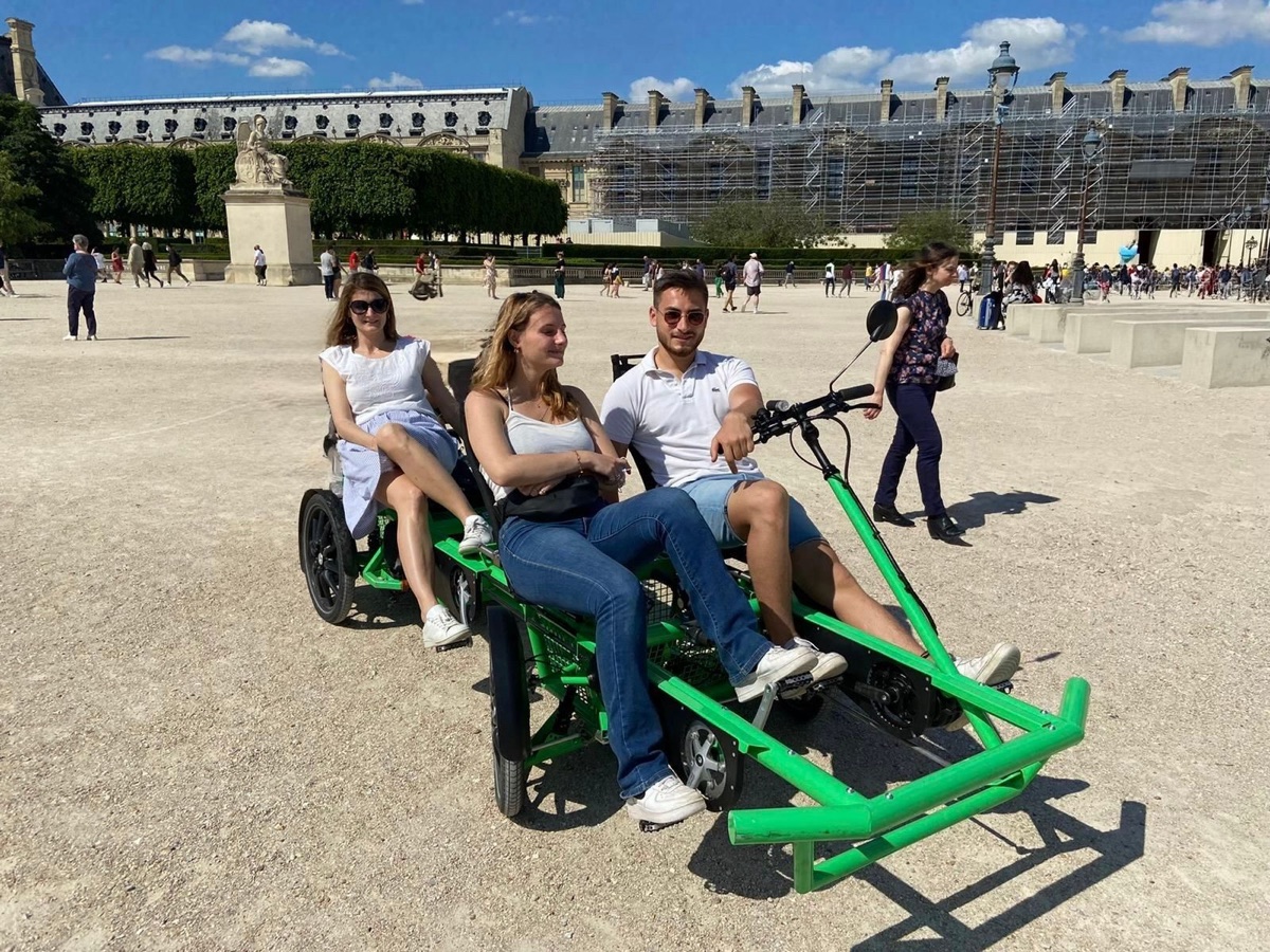 Le premier prototype du OuiCycle, vert et sans toit, avec trois passagers à bord, à Paris.