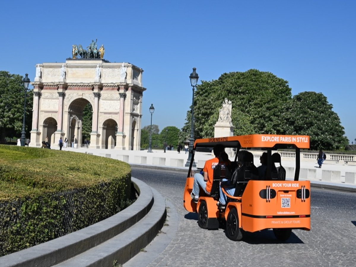 Un OuiCycle orange devant l’Arc de Triomphe du Carrousel à Paris