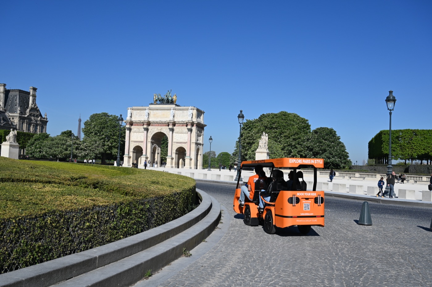 Un OuiCycle orange devant l’Arc de Triomphe du Carrousel à Paris